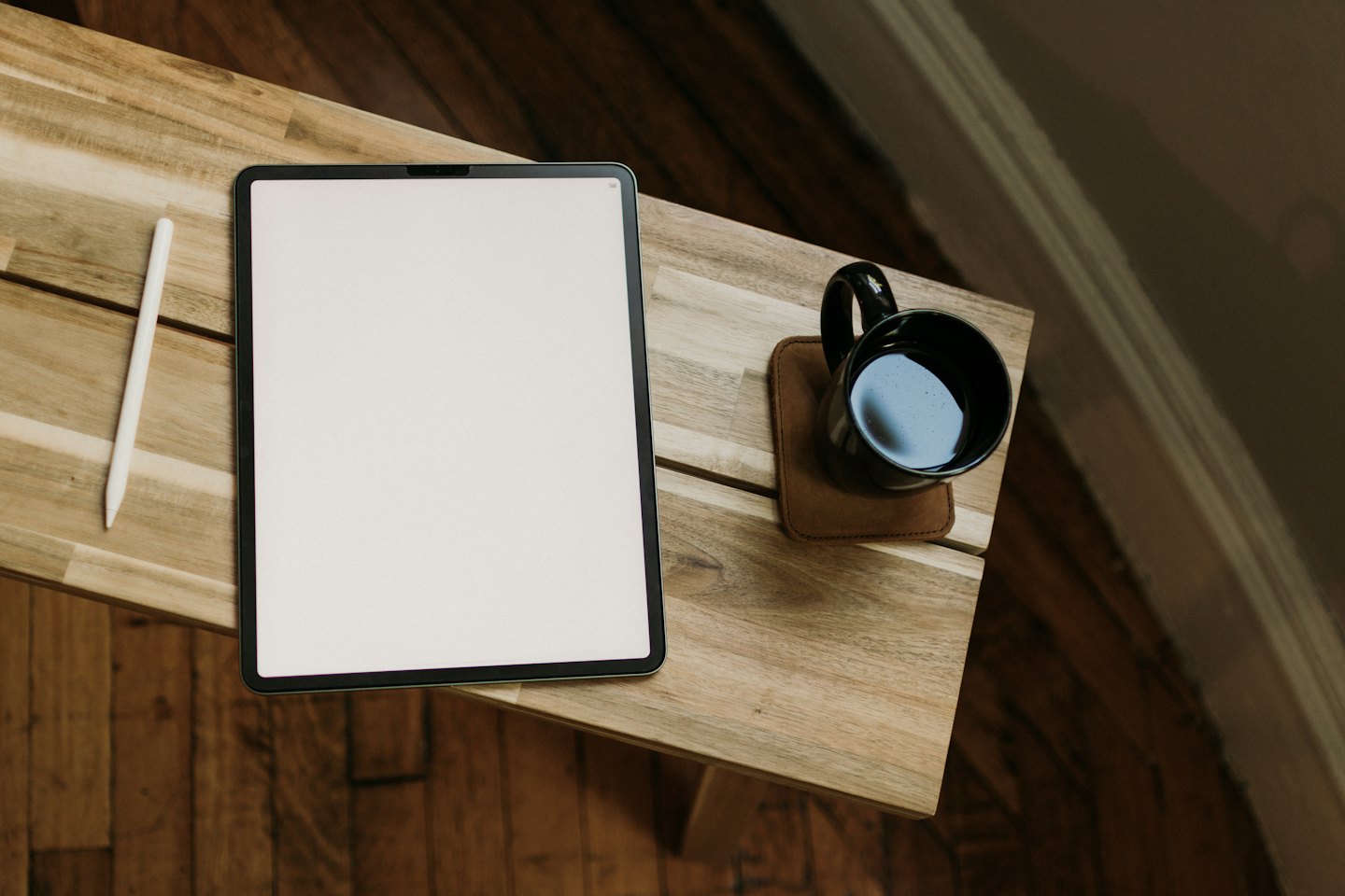 Tablet, rysik i kawa na drewnianym stole.