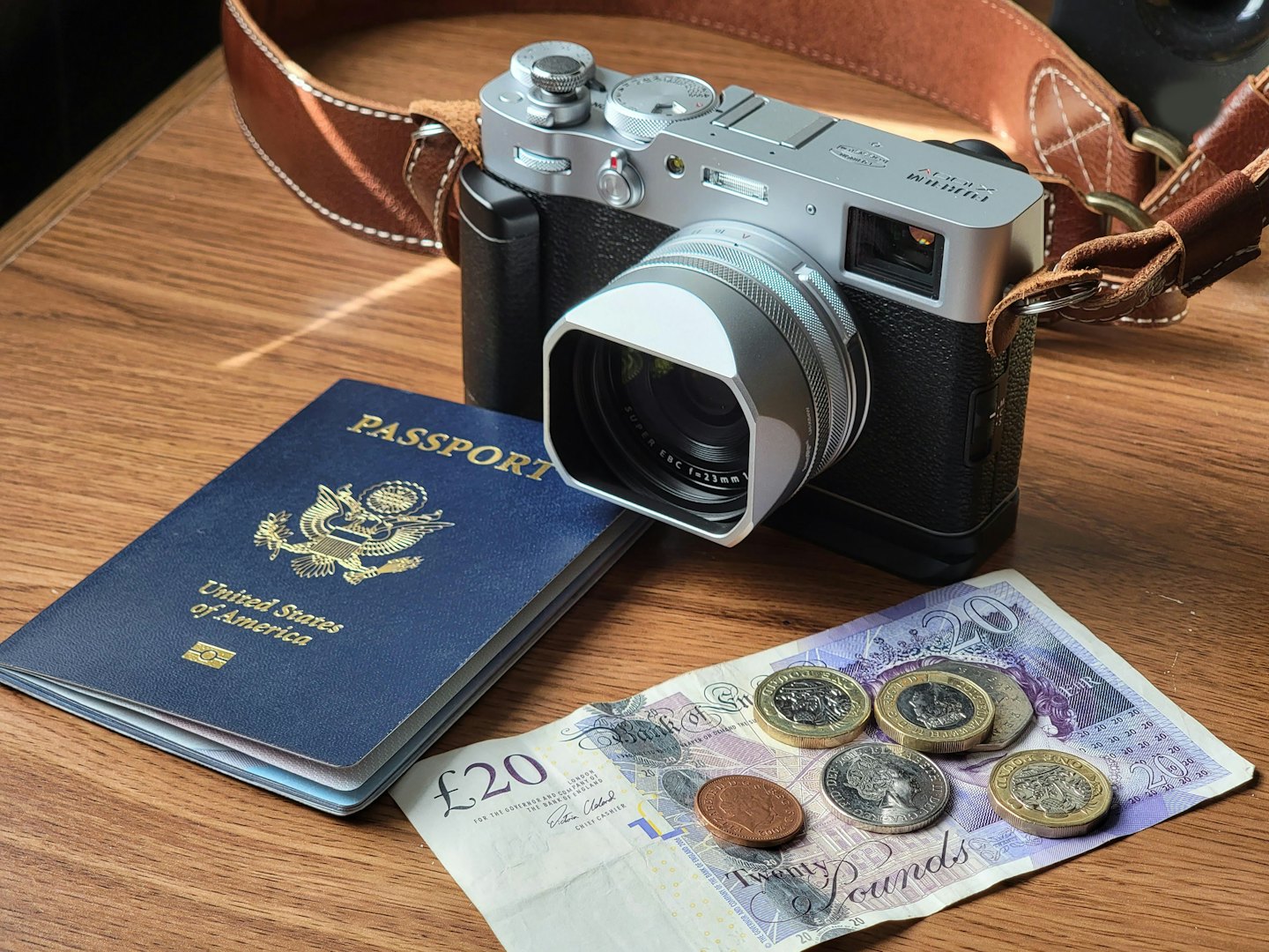 Niezbędne rzeczy do podróży: paszport, waluta i aparat fotograficzny na drewnianym tle.